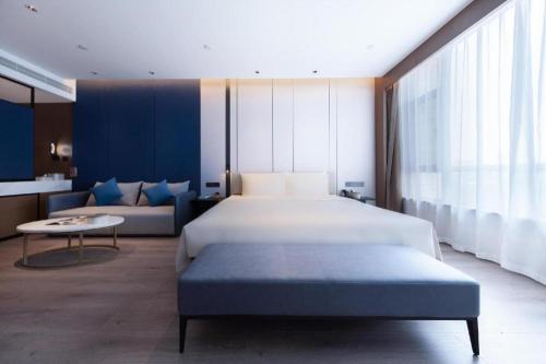 a bedroom with a large bed and a couch at Atour Hotel Jinan Tangyan Dongbaqu Enterprise Park in Jinan