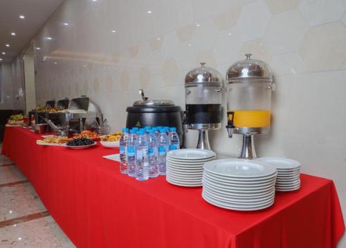 un tavolo rosso con piatti e bottiglie d'acqua di ALAZMI HOTEL a Al Khān
