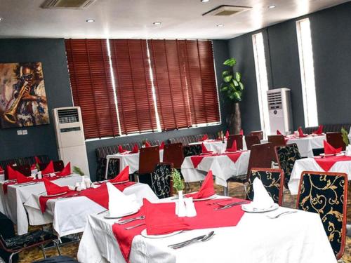 a dining room with red and white tables and chairs at De Edge Hotel in Rumu-Ome