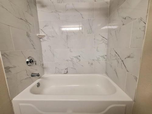 a white bath tub in a bathroom with marble walls at Trident Inn & Suites New Orleans in New Orleans