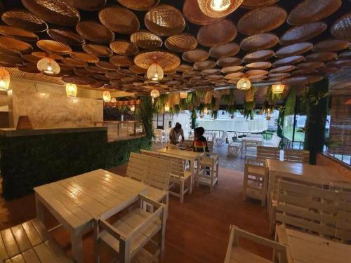 um restaurante com mesas e cadeiras de madeira e um tecto em เมล่อนลอยฟ้า em Ban Kaeo