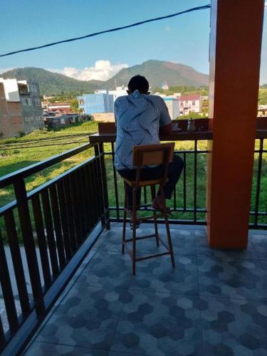 a woman sitting in a chair at a table on a balcony at RAP Hotel Balige in Balige