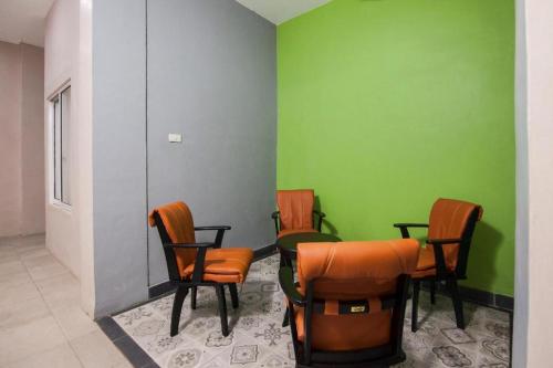um quarto com cadeiras, uma mesa e paredes verdes em RAP Hotel Balige em Balige