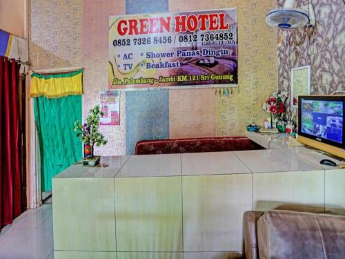 OYO 92024 Green Hotel في جامبي: غرفة مع علامة فندق خضراء على الحائط