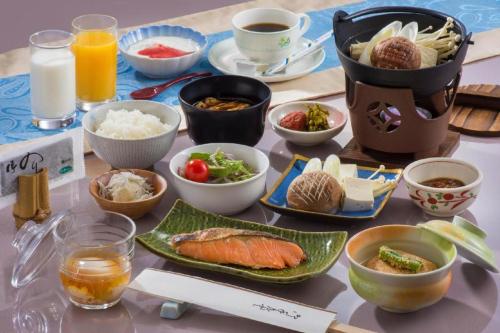 a table with bowls and plates of food and drinks at Matsusaka Wanwan Paradise Mori No Hotel Smeall in Ema