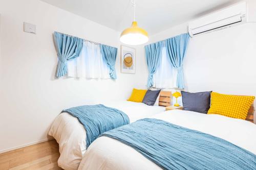 2 camas en una habitación con cortinas azules en Modern House Tokyo east, en Tokio