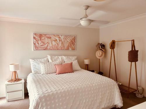 een slaapkamer met een wit bed en een roze kussen bij 5 Well St in Forster