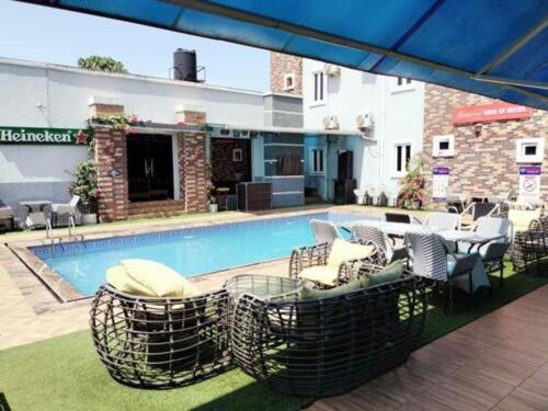 a swimming pool with chairs and a table next to a building at Easton Hill Continental Hotel in Enugu