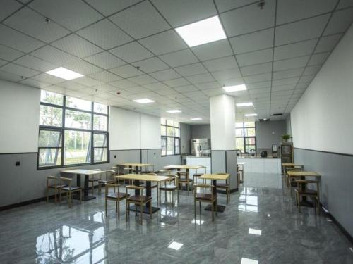 uma grande sala com mesas, cadeiras e janelas em Shell Hotel Chuzhou Nanqiao District Wuyi Town Government Town em Wuyi