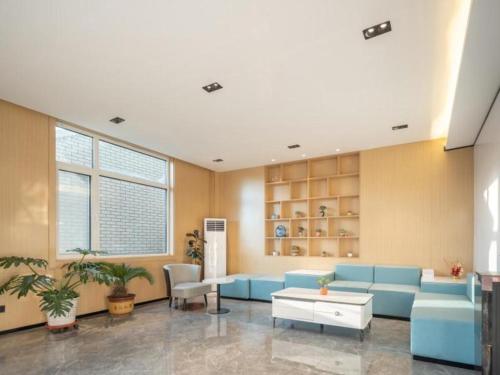uma sala de estar com um sofá azul e uma mesa em GreenTree Inn Express Qingdao Jiaodong International Airport em Ligezhuang