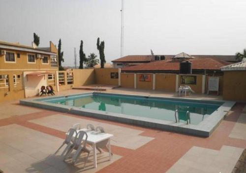 a large swimming pool with two chairs and a table at Adap Hotel in Agbabiaka