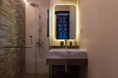 ein Bad mit einem Waschbecken und einer Dusche mit einem Spiegel in der Unterkunft Coco Ville in Nusa Dua