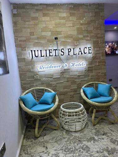 2 Stühle mit blauen Kissen vor einem Geschäft in der Unterkunft Juliet's Place Residence & Hotel in Eregun