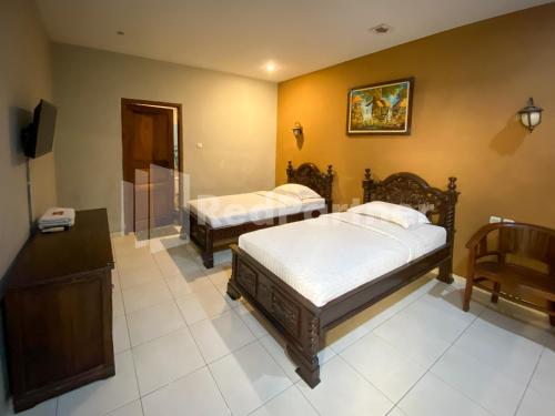 a bedroom with two beds and a television in it at Istana Griya 2 Hotel Solo RedPartner in Solo