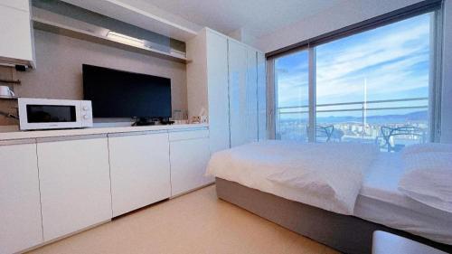 a bedroom with a bed with a microwave and a large window at Yeongjong Shine Hotel in Incheon