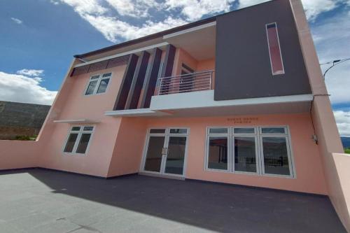 una casa de color rosa en OYO 92504 Guesthouse Porsea en Banualuhu