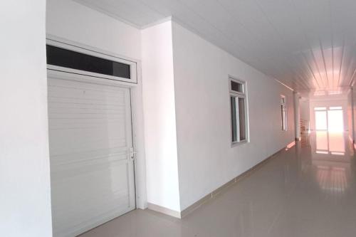 OYO 92504 Guesthouse Porsea في Banualuhu: غرفة بيضاء مع باب كراج ونافذة