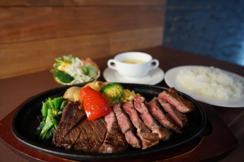 a plate of food with meat and vegetables and a cup of tea at Furano Natulux Hotel in Furano