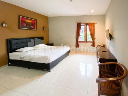 a bedroom with a bed and a dresser and a desk at Istana Griya 2 Hotel Solo RedPartner in Solo