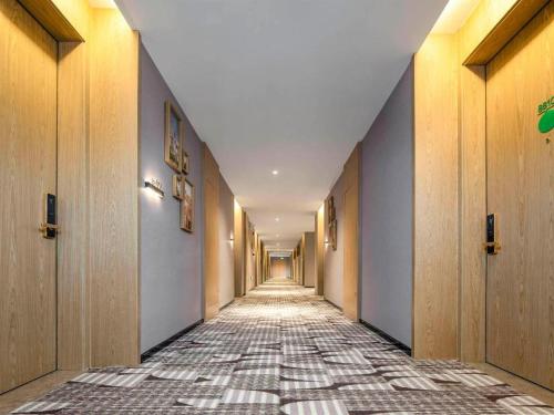 a hallway with a tile floor and a long corridor at Campanile Hotel Shenzhen Guanlan Goft in Tiantangwei