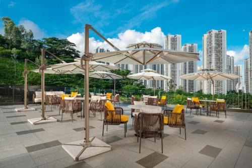 patio ze stołami, krzesłami i parasolami w obiekcie AMIGO migo Sleeping Hotel (mission hills) w mieście Tiantangwei