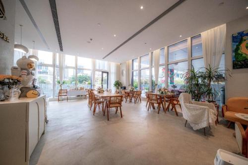 a dining room with tables and chairs and windows at F-TOWN Fangtang Hotel (Shenzhen Longgang Tian'an Digital City Huanggekeng Subway Station) in Longgang