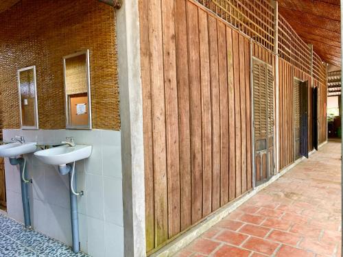 La salle de bains est pourvue de 2 lavabos et de murs en bois. dans l'établissement Hometravel Mekong Can Tho, à Cần Thơ
