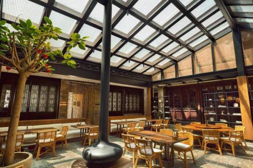 a restaurant with tables and chairs and a glass ceiling at Blossom House Xuzhou Huilongwo Banyunting in Xuzhou