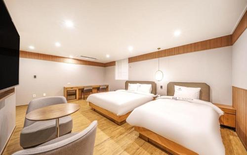 um quarto de hotel com duas camas e uma mesa em H Avenue Gyeongju em Gyeongju