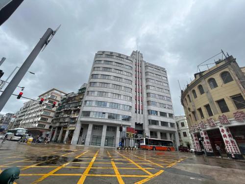 un edificio alto en una calle de la ciudad con un autobús en Grande Hotel Macau en Macao