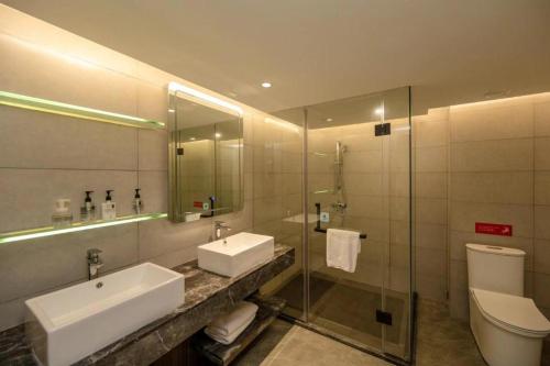 W łazience znajduje się umywalka, toaleta i lustro. w obiekcie Echarm Hotel Zhanjiang Zhanchuan Avenue Wanda Plaza w mieście Zhanjiang