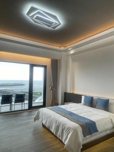a bedroom with a large bed and a large window at 愛琴海岸精品民宿 in Fangliao