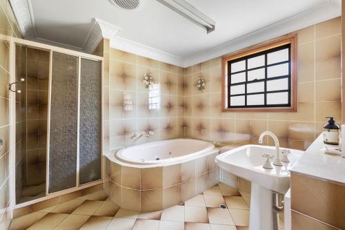 baño grande con bañera y lavamanos en Ocean Shores Waterfront 5 Bedroom Home Including SAUNA room, en Kioloa