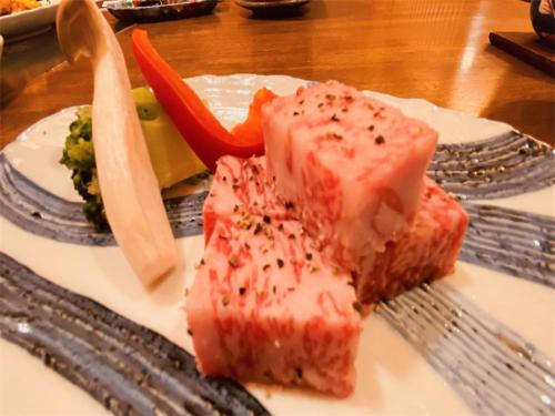 un plato blanco con un trozo de comida en un tenedor en Hotel & Onsen 2307 Shiga Kogen, en Shiga Kogen