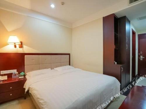 een slaapkamer met een groot wit bed en een bureau bij Bashan Hotel in Heshan