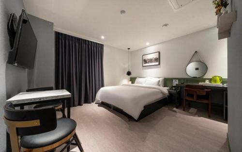um quarto de hotel com uma cama, uma secretária e um computador em Wonju Bellino Hotel em Wonju