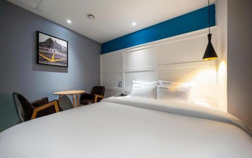 a bedroom with a large white bed and chairs at Wonju Bellino Hotel in Wonju