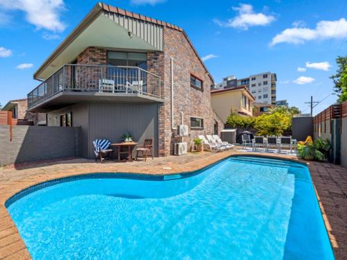 a swimming pool in front of a house at Ocean Park Motel & Holiday Apartments in Coffs Harbour