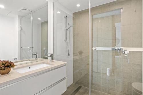 uma casa de banho com um lavatório e uma cabina de duche em vidro. em Executive 2-Bed with Stadium View, Great Amenities em Brisbane