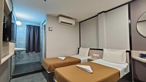 a small hotel room with two beds and a mirror at Urban Inn, Jitra in Jitra