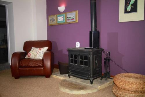 a living room with a stove and a chair at One Bedroom Character Cottage in Farthinghoe