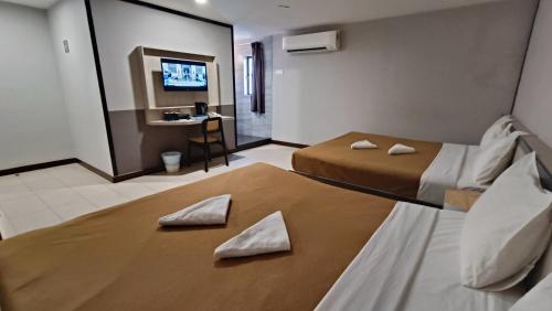 a hotel room with two beds and a desk at Urban Inn, Jitra in Jitra