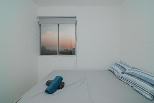 um quarto branco com uma cama e uma janela em Apartamento El Colibri Cartagena en torre PRIMI em Cartagena das Índias