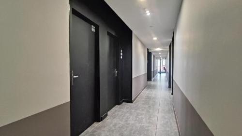 a hallway with black doors and a tile floor at Urban Inn, Jitra in Jitra