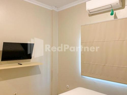 a room with a tv and a window with a blind at Hotel Andono RedPartner near YIA in Yogyakarta