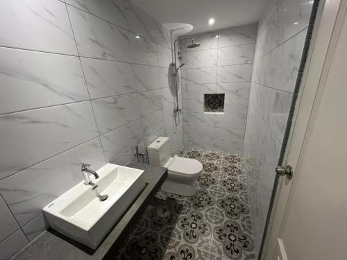 a white bathroom with a sink and a toilet at The Farmhouse in Ipoh