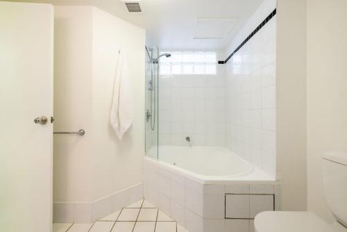 uma casa de banho branca com uma banheira e um WC em The Landmark unit 405 - Resort style, spectacular water views, linen, pool, lift, games room, porta-cot and highchair em Nelson Bay