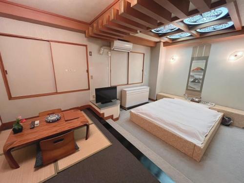 um quarto com uma cama, uma mesa e uma televisão em チョコレ新潟 em Higashi-horidōri