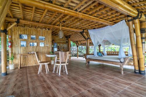 a bedroom with a bed and a table and chairs at Catappa Village Lombok in Sekotong