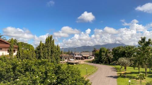 a dirt road in a village with trees and houses at น่าน ม่วนใจ Nan Muanjai Hotel in Pua